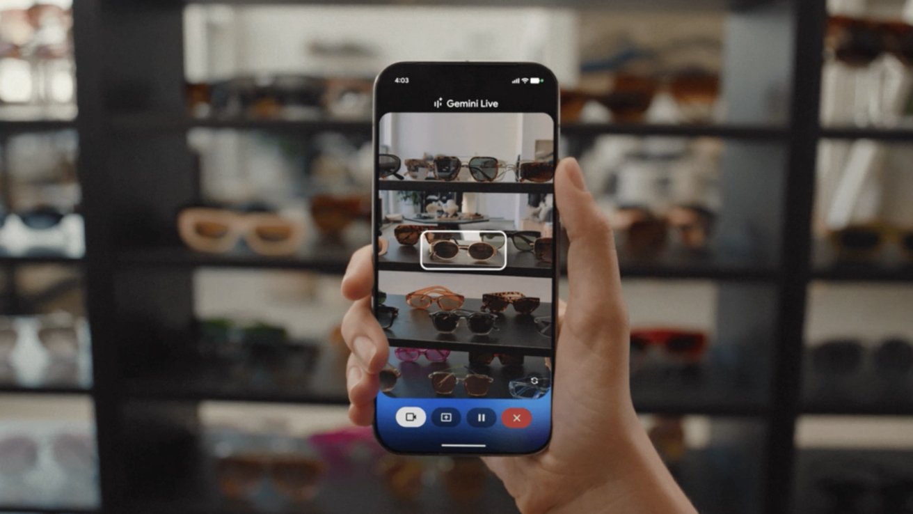 Person holding a smartphone with a camera app focused on sunglasses displayed on shelves in the background.