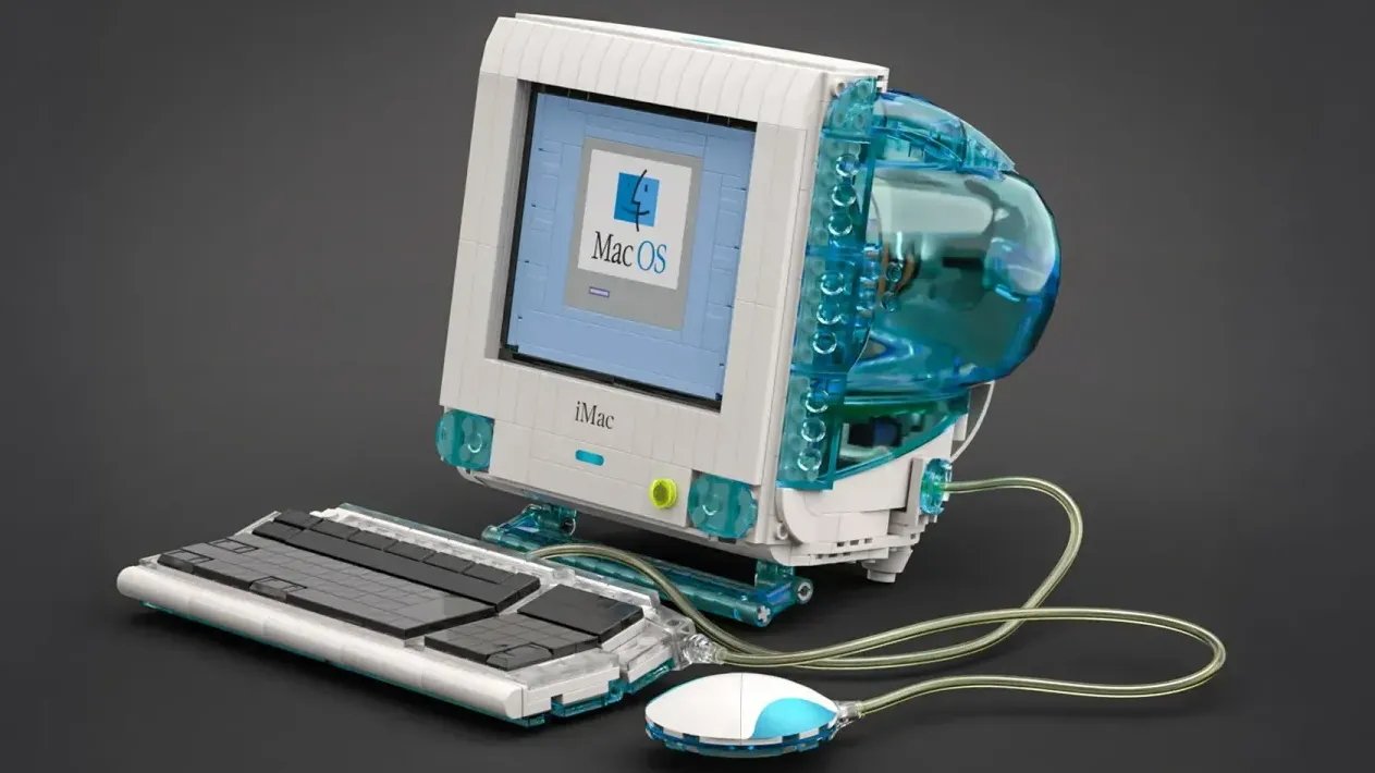 LEGO model of a vintage iMac computer with a clear blue shell, gray keyboard, and wired mouse on a dark background.
