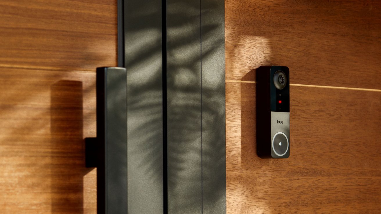 The dark handle of the door and an intelligent bell mounted on the wooden surface, while the sunlight creates soft shadows through the scene.