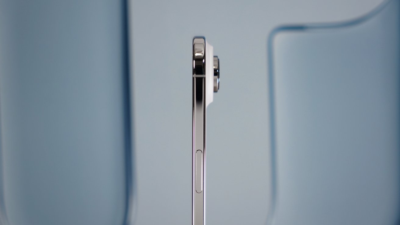 Side view of a thin, silver smartphone with a protruding camera against a blurred blue background.