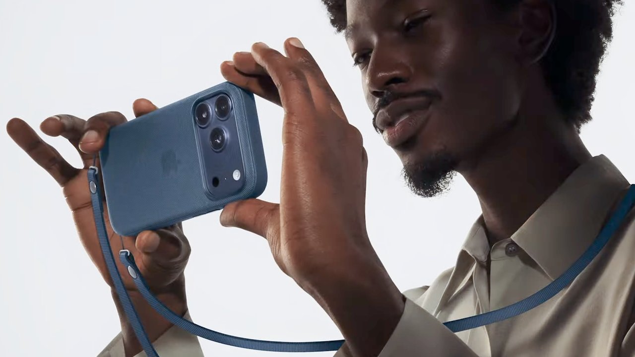 Person holding a blue smartphone camera, using a strap for support, with a focused expression.
