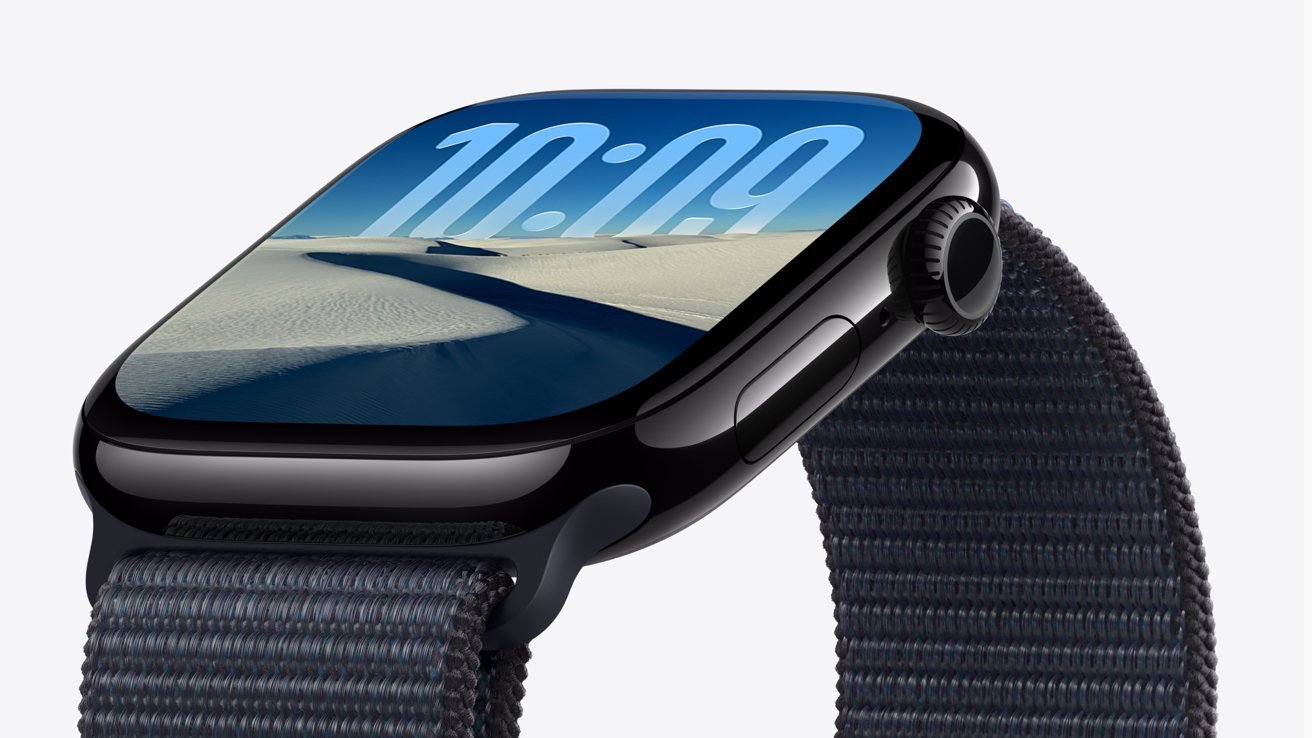 Smartwatch with black frame, fabric band, and a digital display showing 10:09 over a sandy desert landscape background.