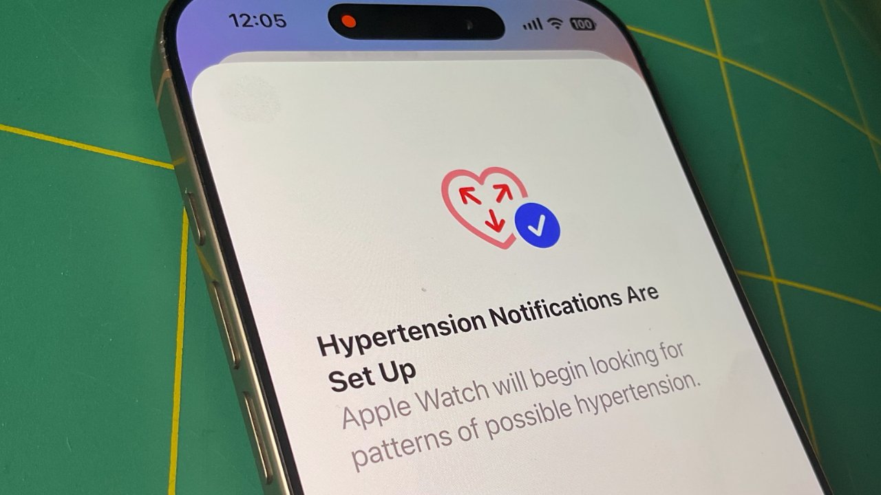 Smartphone displaying a 'Hypertension Notifications Are Set Up' message with a heart and checkmark icon, green surface in background.