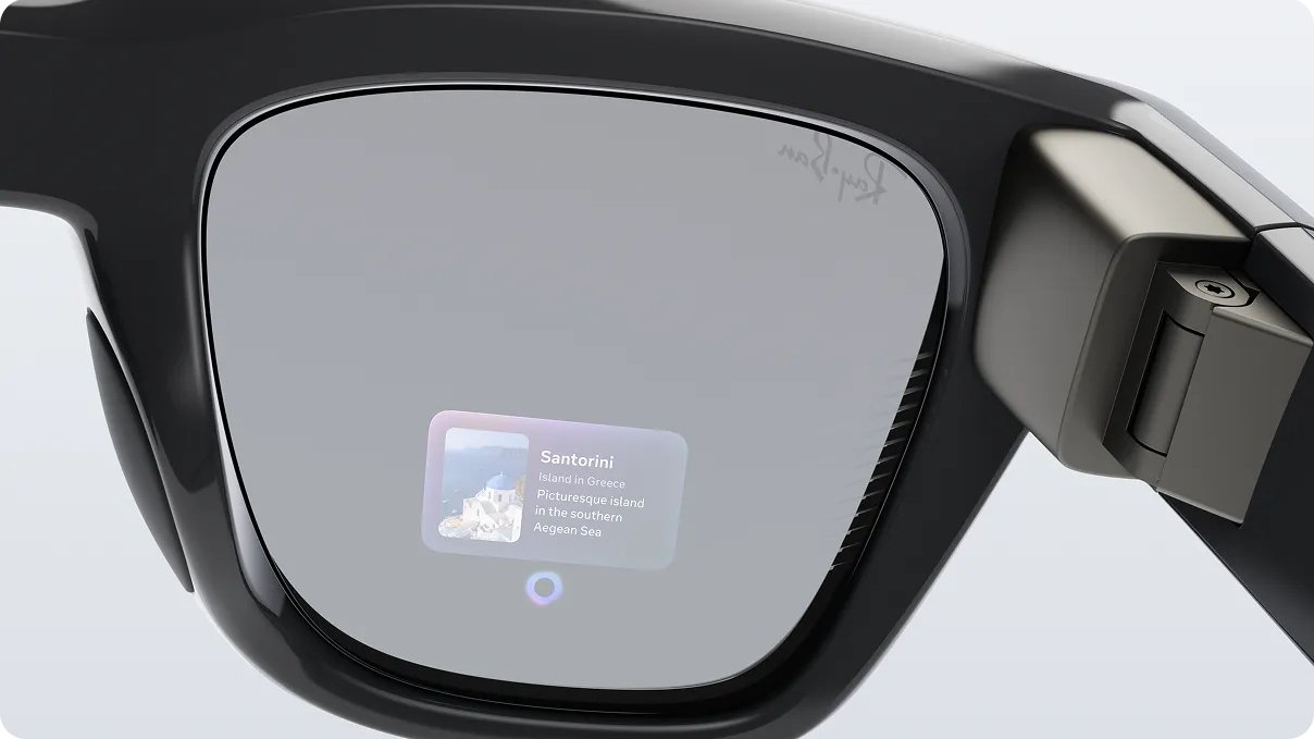 Lens of smart glasses showing digital information about Santorini, Greece, including a picture of a white building and a blue sky. Goggles have an elegant black frame.