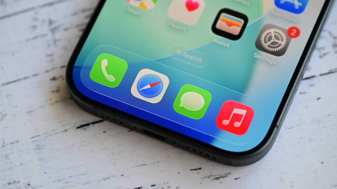 Close-up of a smartphone screen displaying apps such as Safari, Messages, Phone, and Music with notifications on a wooden surface.