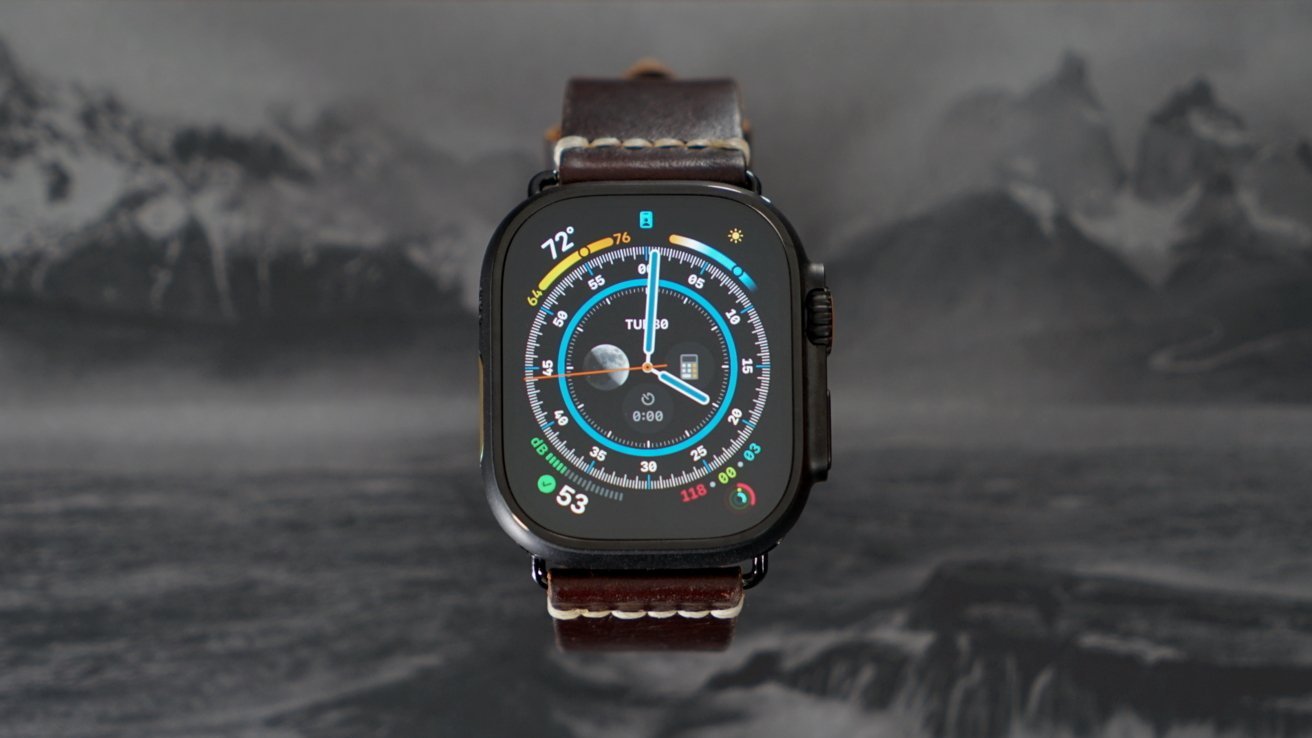 Smartwatch with a dark leather strap displaying colorful weather, compass, and activity widgets on its screen against a blurred mountain backdrop.