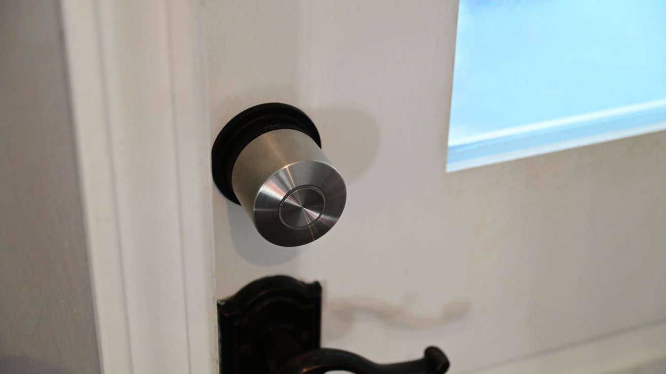 Silver deadbolt lock on a white door with a glass window above a dark lever handle.