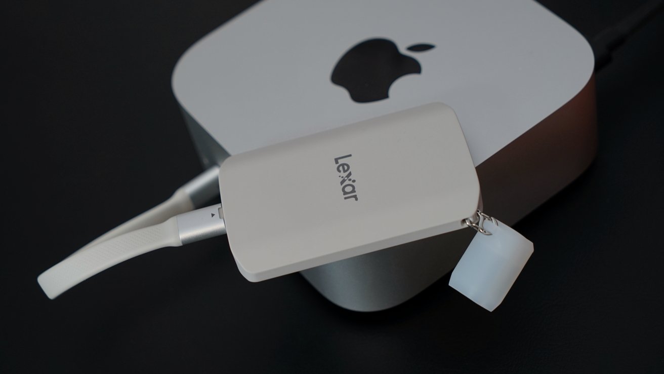 White Lexar USB drive connected to a computer, featuring an Apple logo, on a dark surface.