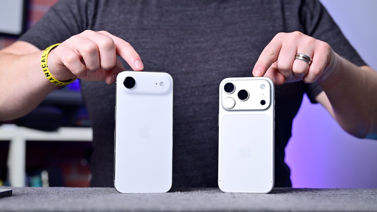 Two hands holding white smartphones with different camera layouts, one having two cameras and the other three, against a dark background.