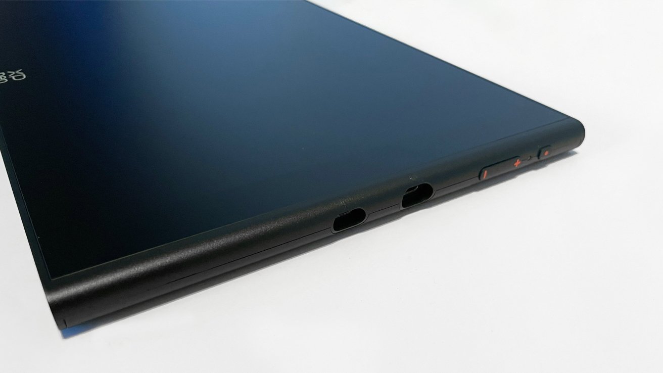 Black tablet with sleek design, thin edges, and visible ports and buttons along its curved side, placed on a white surface.