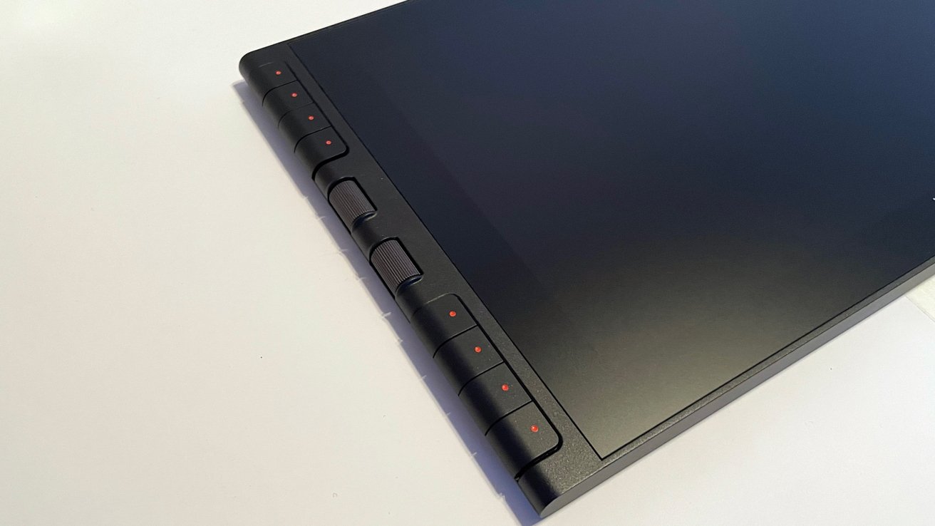 Black tablet with several side buttons, featuring small red dots above each. The screen occupies most of the surface.