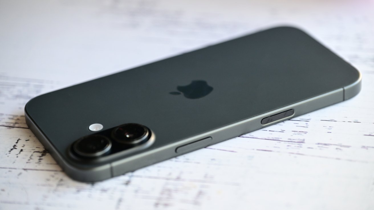 A sleek, gray smartphone lies flat on a lightly textured surface, featuring dual cameras and a small logo in the center.