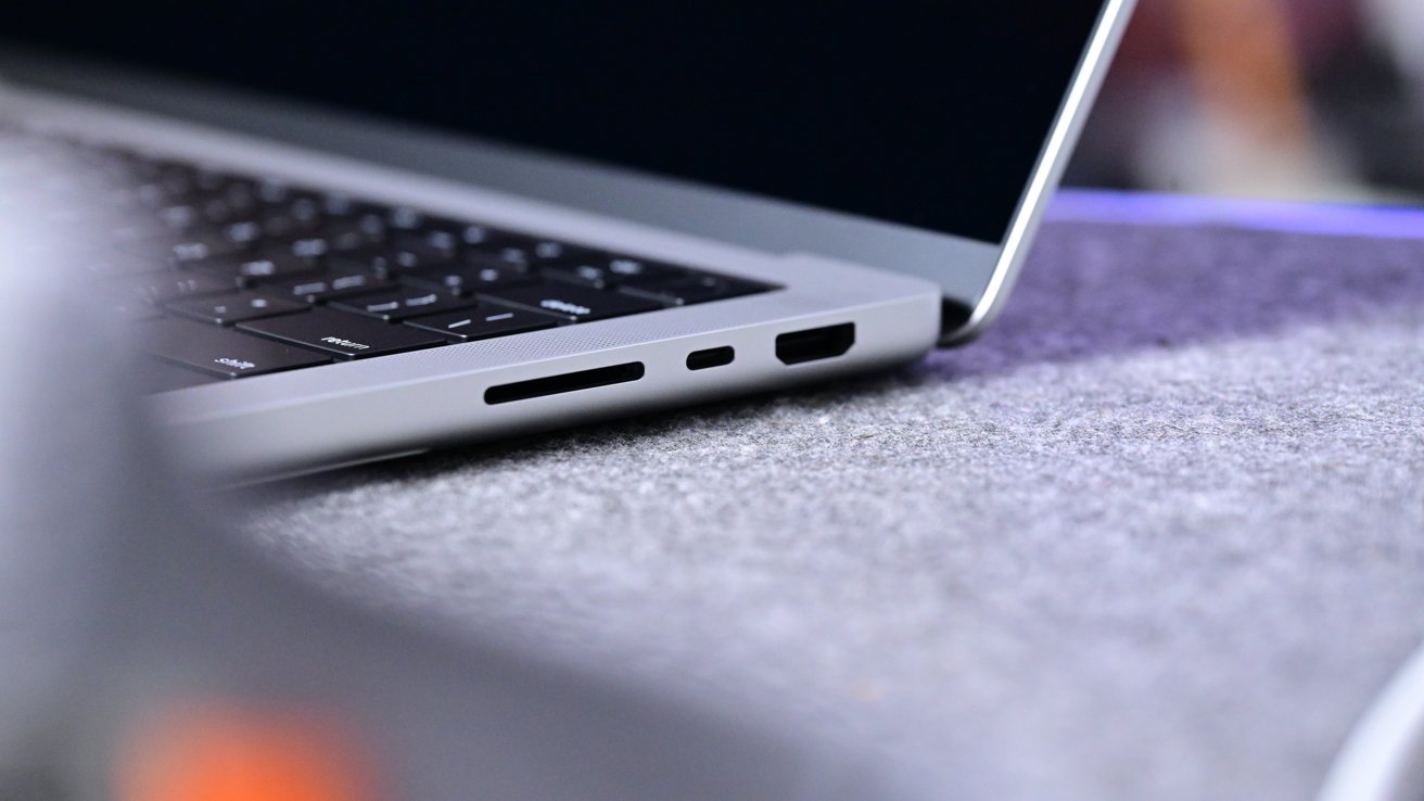 Close-up of a silver laptop showing keyboard and side ports, resting on a textured gray surface.