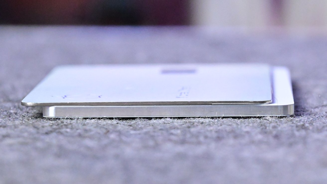 Two stacked rectangular metal cards with slightly rounded edges on a textured gray surface. The cards appear thin and show their layered design when viewed from the side.