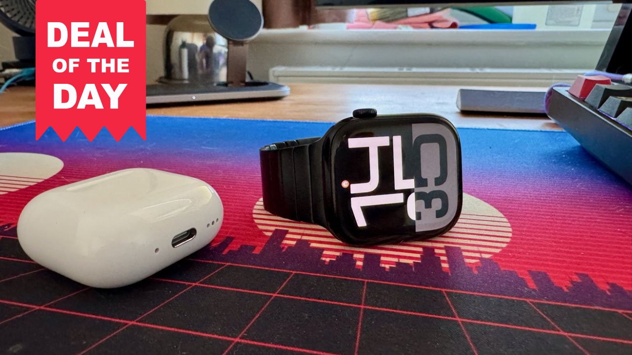 Apple Watch with black band next to AirPods on desk mat and Deal of the Day banner.