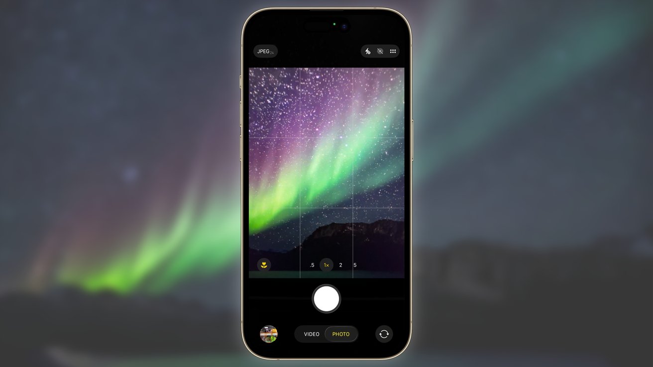 Smartphone screen displays a vibrant aurora borealis with green and purple lights over a starry night skybackground.