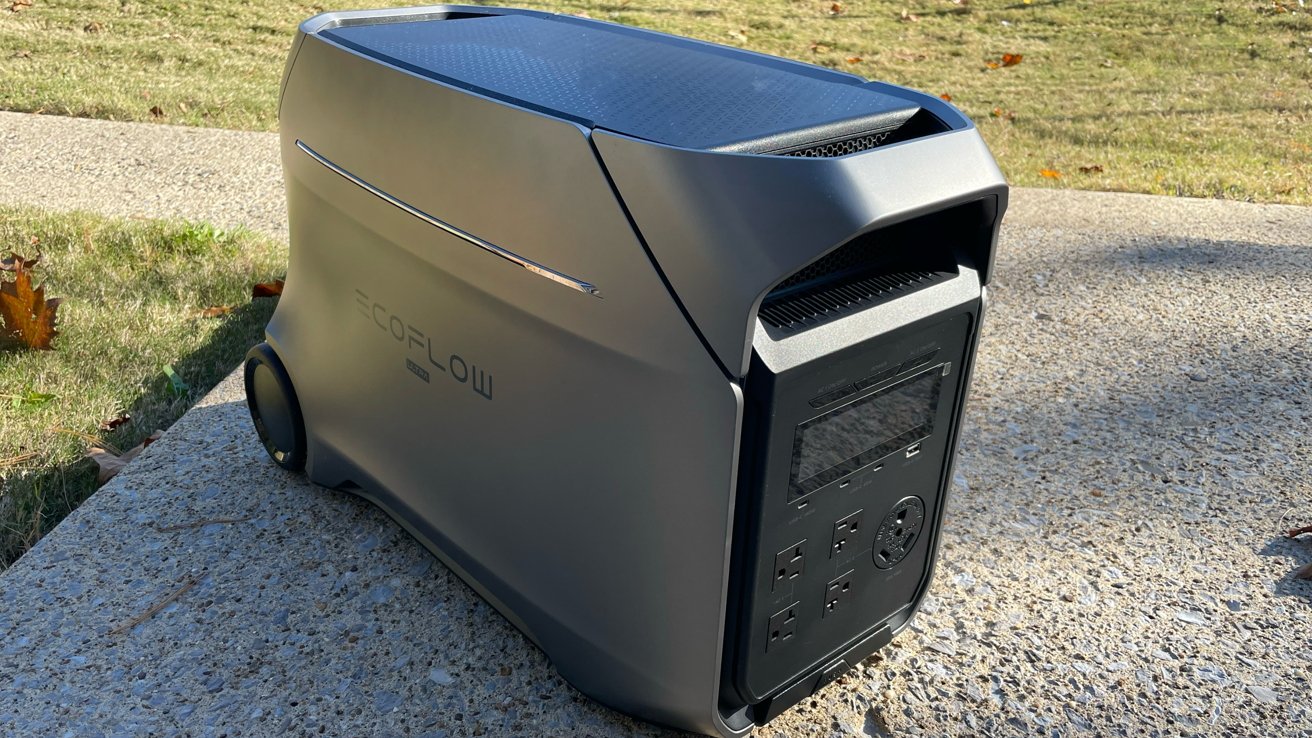 Portable power station on a concrete path with grass in the background, featuring multiple outlets and a sleek, modern design.