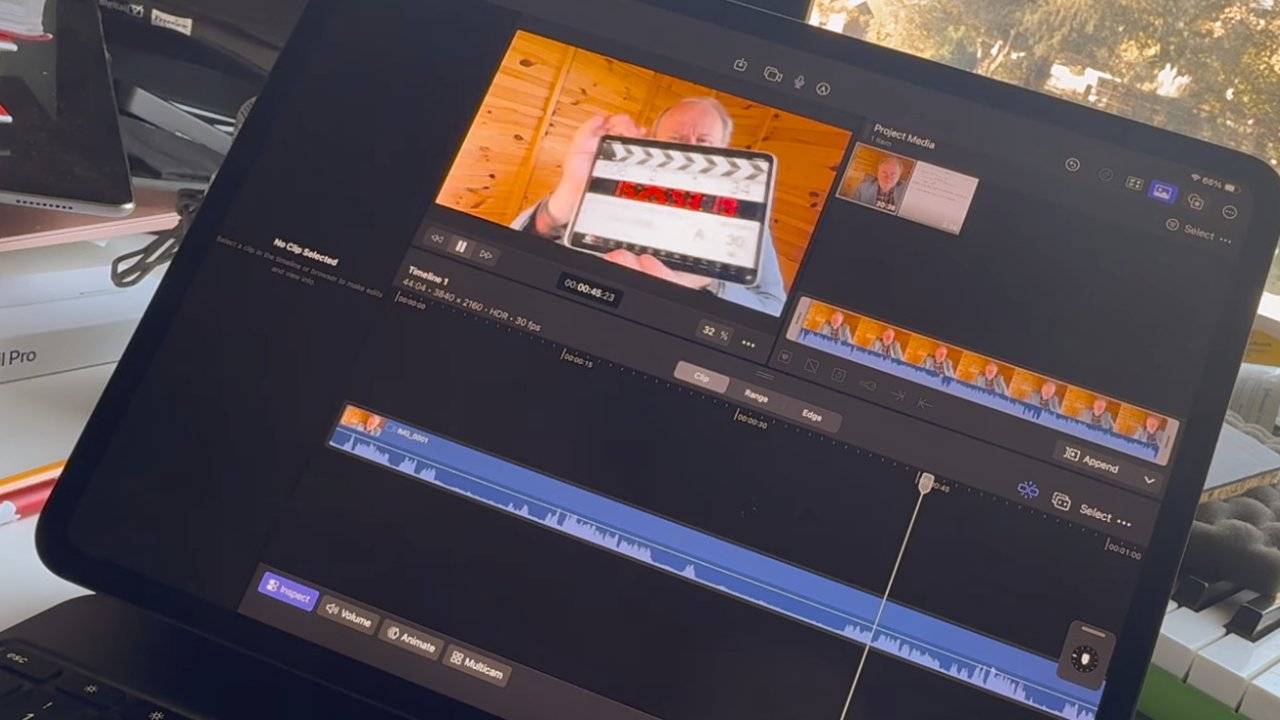Laptop screen displaying video editing software with a clapperboard visible. Visible windows and desk clutter in the background.