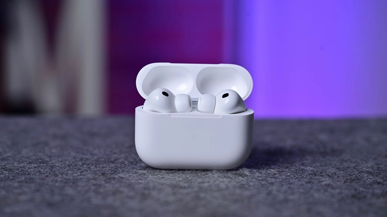 White wireless earbuds in an open charging case on a gray surface with a purple background.