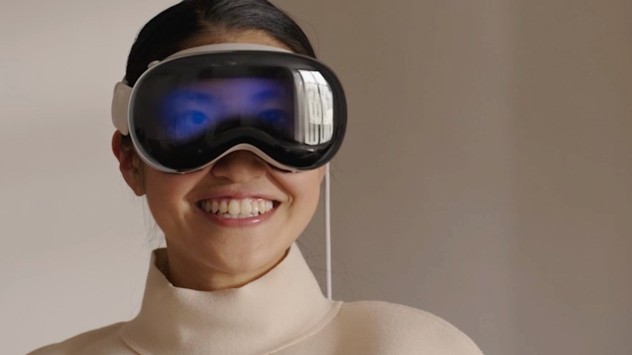 Person smiling, wearing a large virtual reality headset, in a light-colored room.