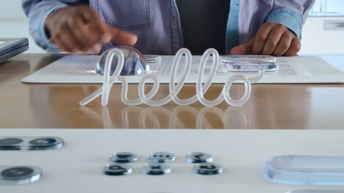 Clear cursive 'hello' sculpture, person seated at a desk with braille documents, magnifying lenses, and buttons in the foreground.
