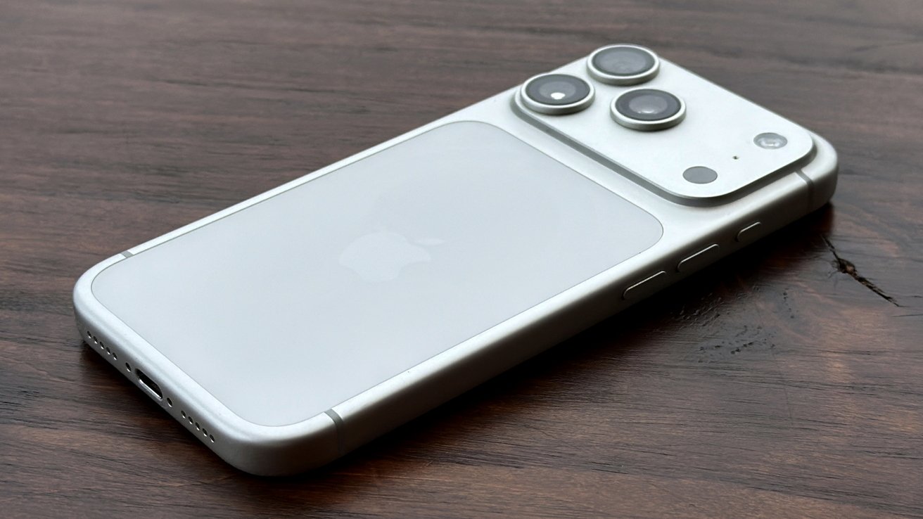 Smartphone lying on a wooden surface, displaying three camera lenses and an Apple logo on the back.