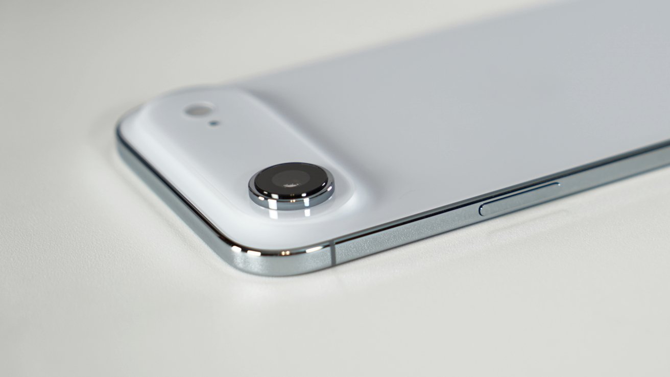 Close-up of a sleek, white smartphone back, featuring a raised camera lens and a metallic edge on a white surface.