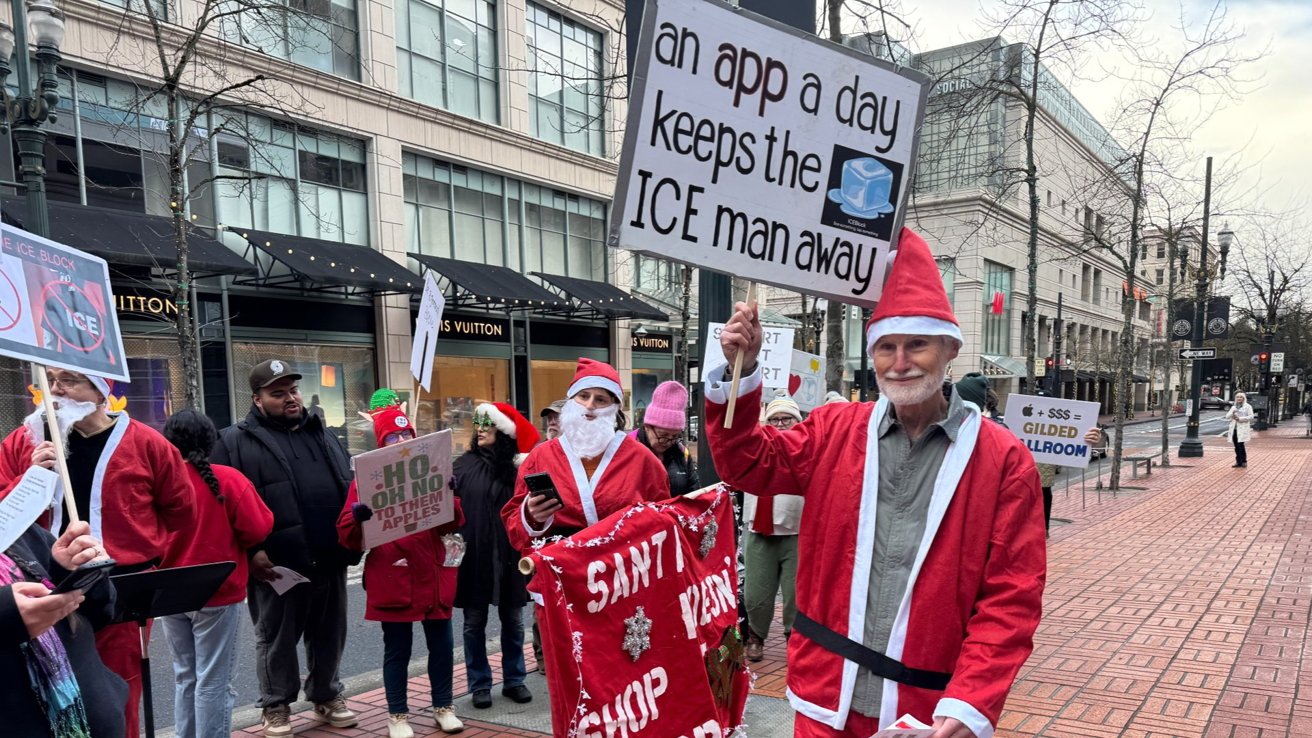 People in Santa outfits holding signs in a city street, participating in a protest or demonstration.