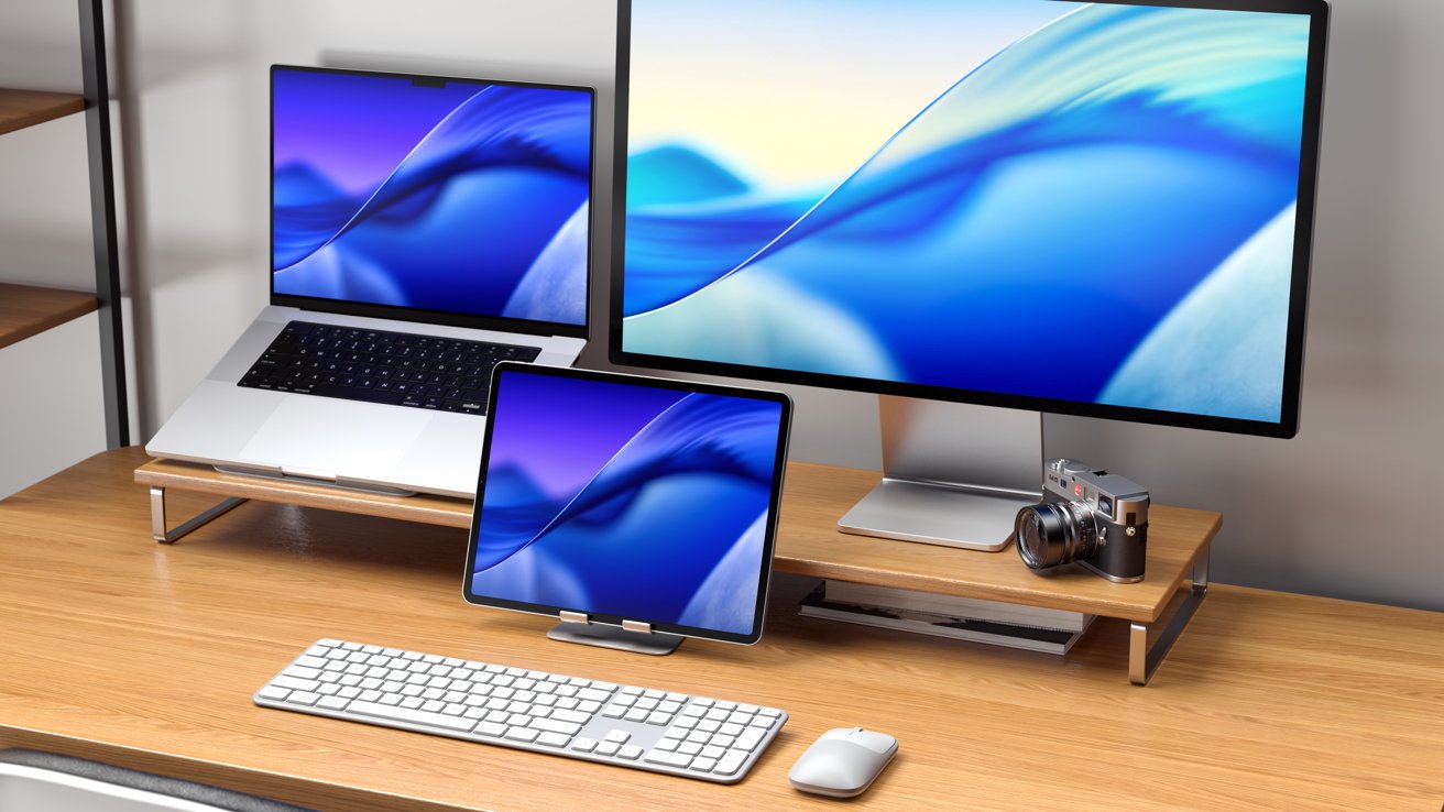A sleek desk setup with a laptop, tablet, and monitor displaying blue wave graphics, accompanied by a keyboard, mouse, and a camera on a wooden stand.