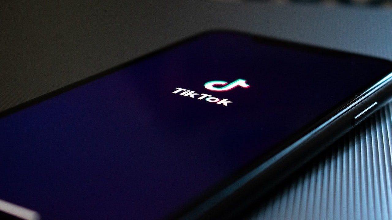 Smartphone screen with TikTok logo and app name on dark background, close-up angle.