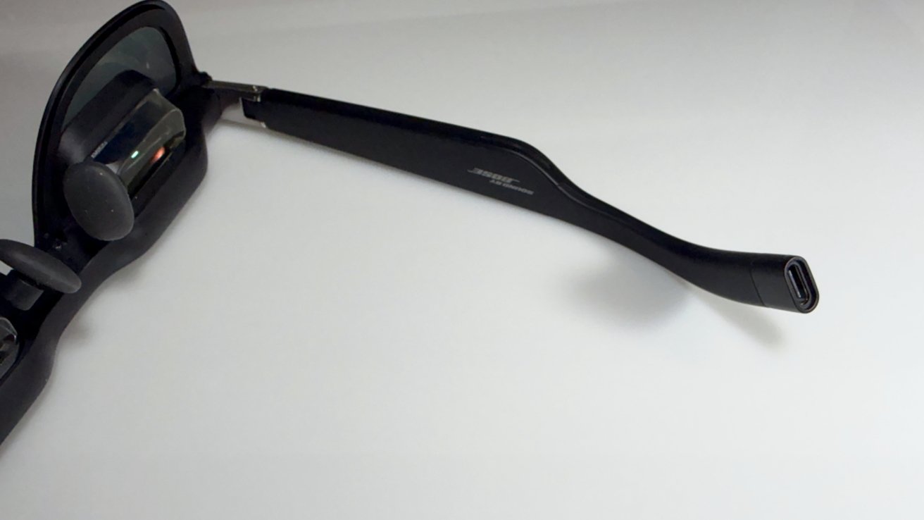 Sunglasses with elegant black frames with integrated technology on a clean white background. Right arm extended towards the viewer.