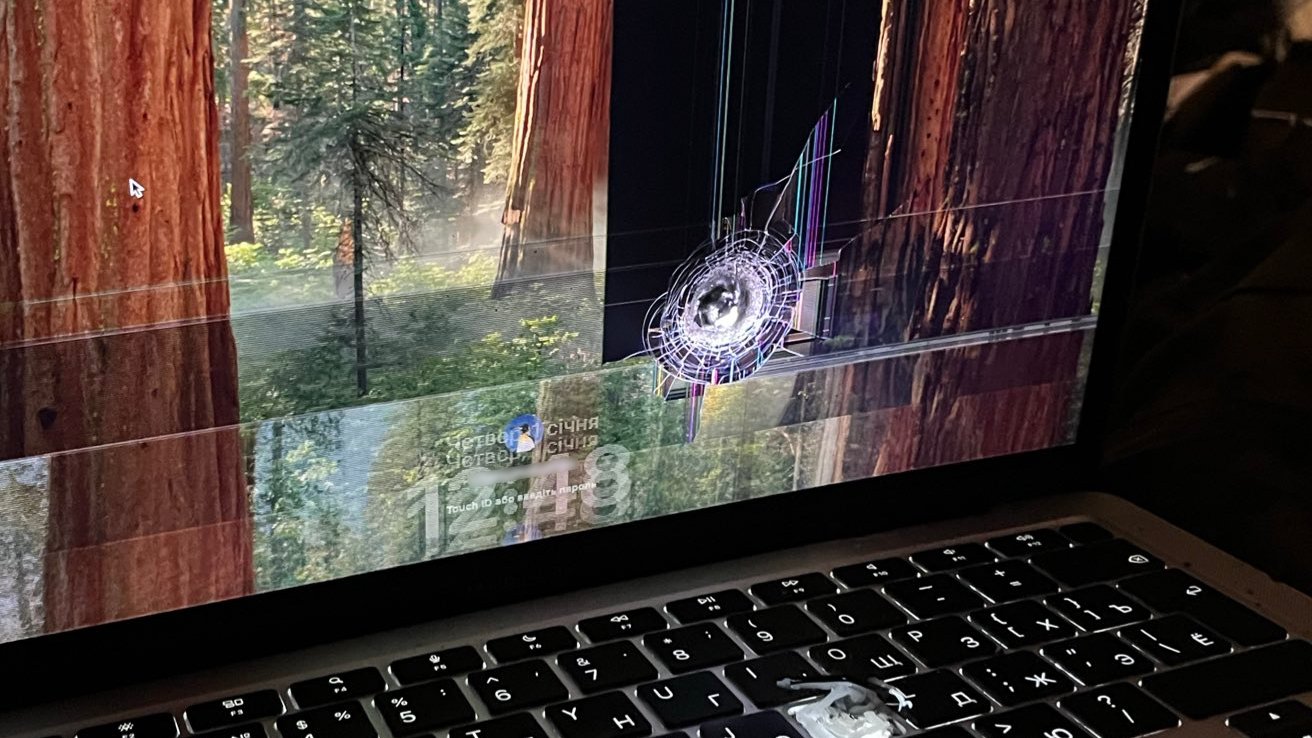 Laptop screen displaying a forest background with noticeable screen damage and colorful digital distortion on the right side. Keyboard with Cyrillic letters visible.