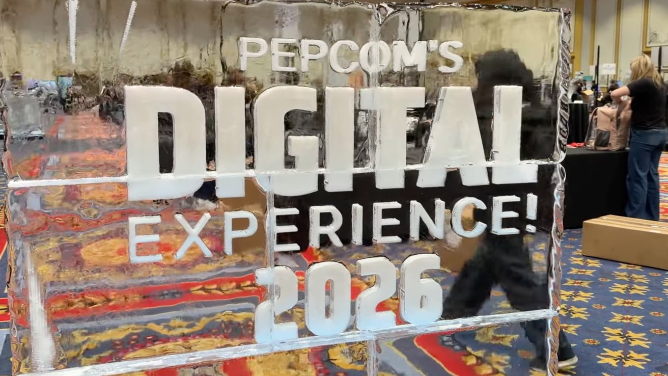 Ice sculpture with 'Pepcom's Digital Experience 2026' text, colorful carpet, people in background.