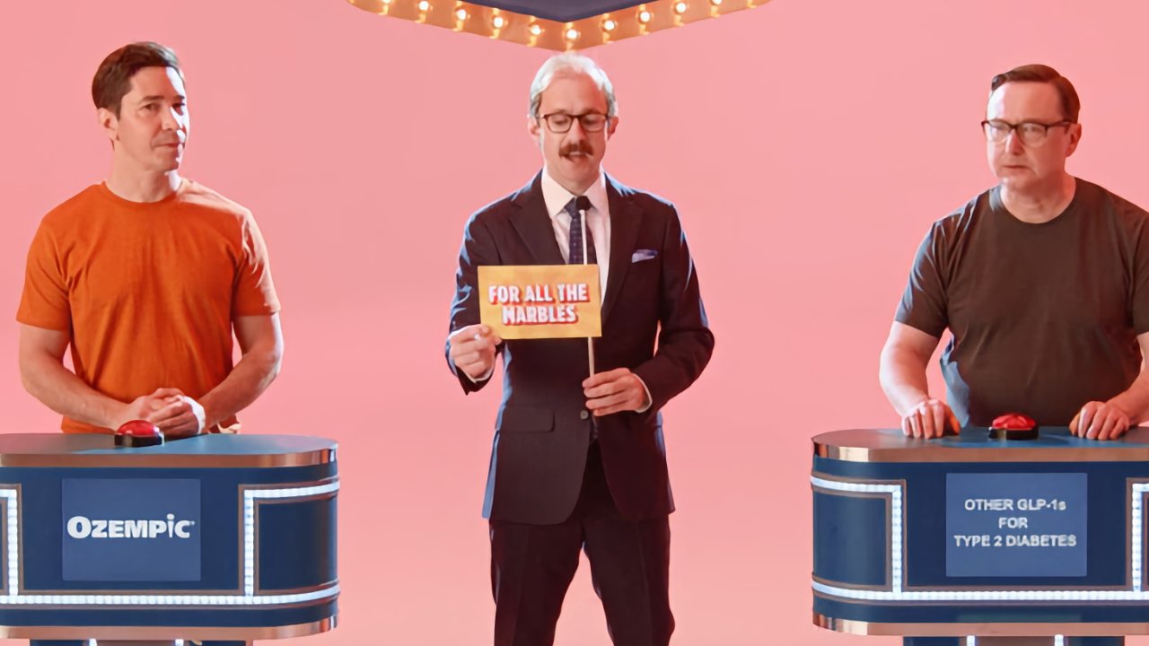 Game show scene: suited host holds sign reading 