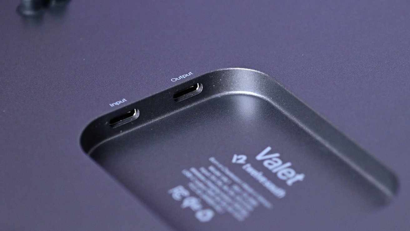 Close-up of a sleek electronic device labeled Valet with an inset area showing two USB-C style ports labeled input and output on a smooth dark metal surface