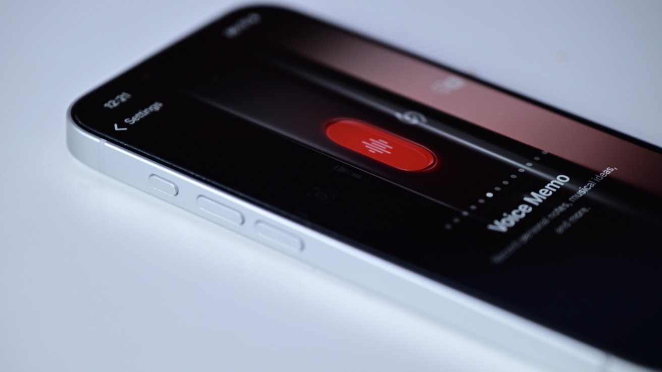 Close-up of a smartphone on a white surface displaying a recording app with a large red record button and text reading Voice Memo