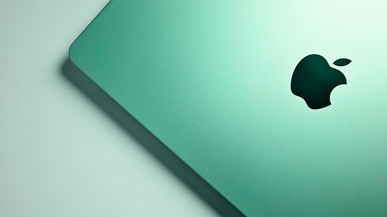 Close-up of a teal-colored Apple laptop lid, showing the dark Apple logo on a smooth metallic surface with soft lighting and gentle shadow along the edge