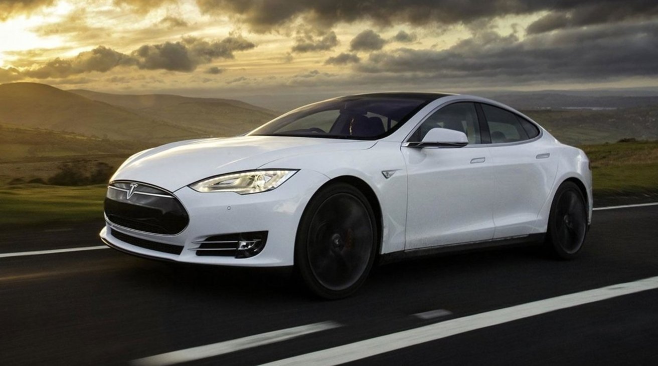 White Tesla sedan driving on an open highway at sunset, motion blurred wheels, rolling green hills and dramatic cloudy sky in the background