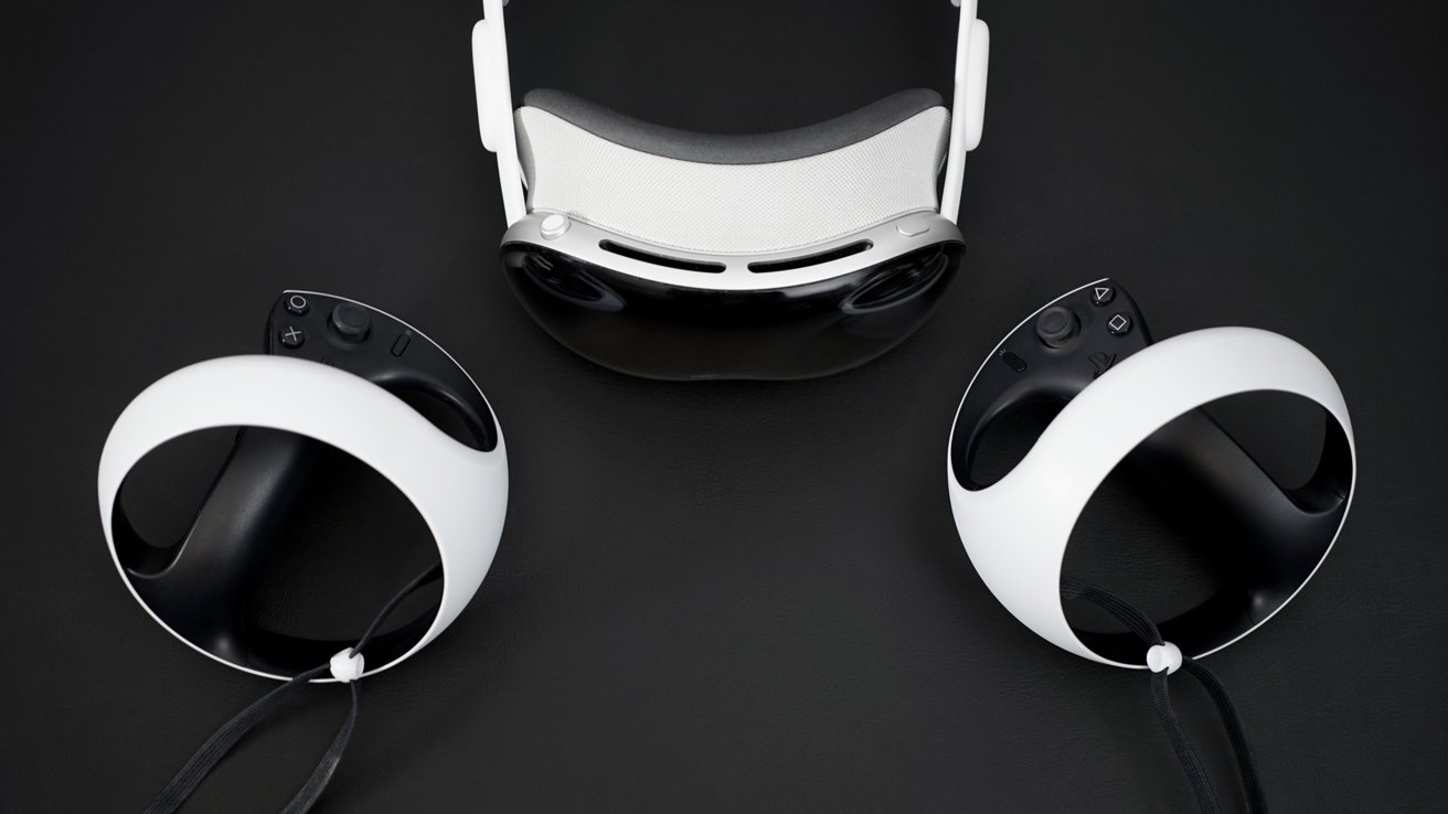 The Apple Vision Pro VR headset on a black surface by two PlayStation VR2 controllers