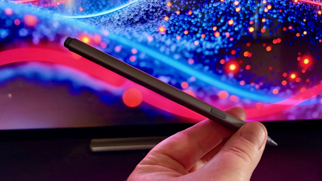 Hand holding a sleek digital stylus in front of a vibrant, abstract computer screen with bright blue, red, and purple lights and soft bokeh patterns.