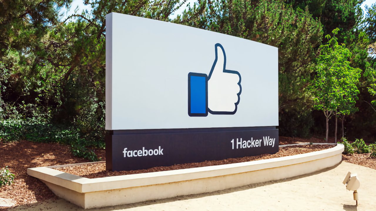 Large outdoor Facebook sign featuring a blue thumbs up logo and text reading Facebook and 1 Hacker Way, surrounded by trees and landscaping under clear daylight