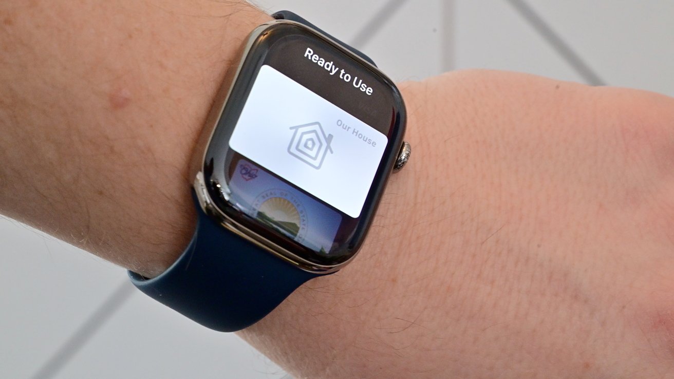 Smartwatch with a dark blue band on a person's wrist, screen showing a smart home app setup message reading Ready to Use with a house icon