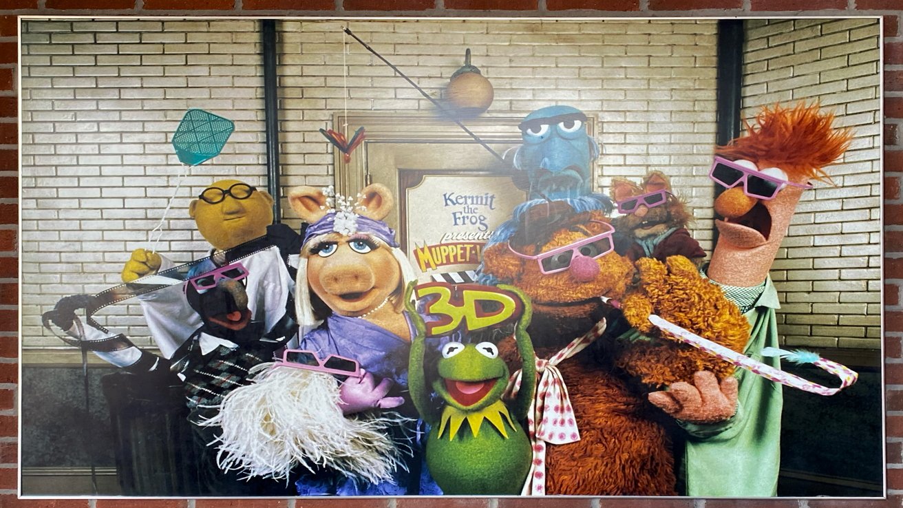 A poster for the 'Muppet*Vision 3D' ride showing the cast of characters, including the green frog Kermit, who is holding a sign that says '3D'