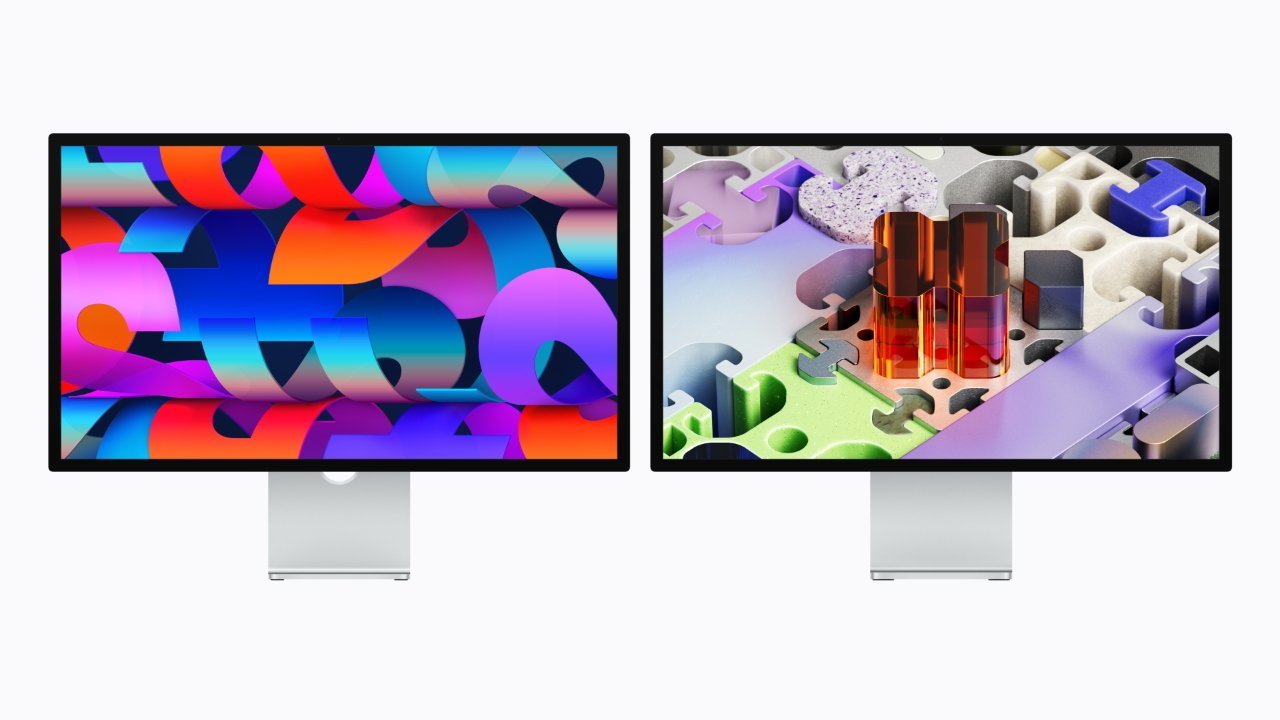 Two sleek, silver Apple desktop monitors side by side, each showing vibrant abstract artwork with bold colors and geometric shapes on a clean white background