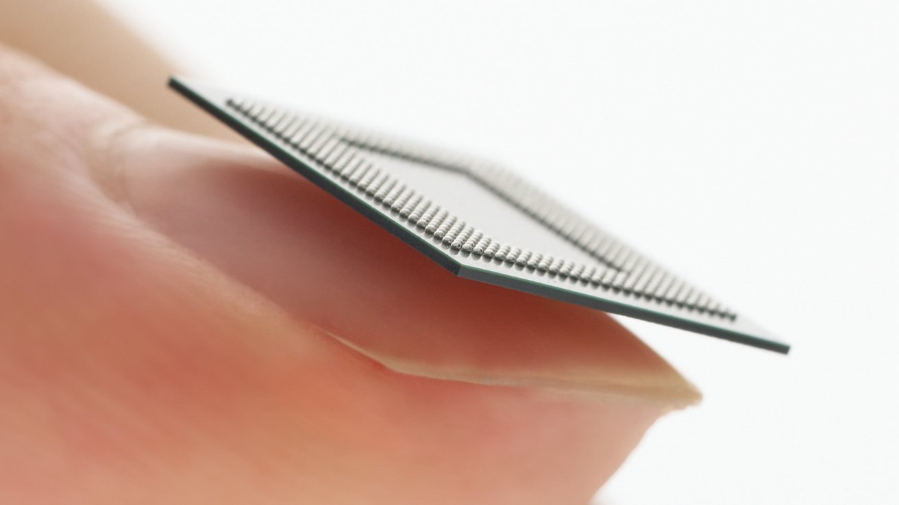 Close-up of a fingertip delicately holding a thin computer microchip, showing its tiny metallic contact points in sharp focus against a soft, bright background