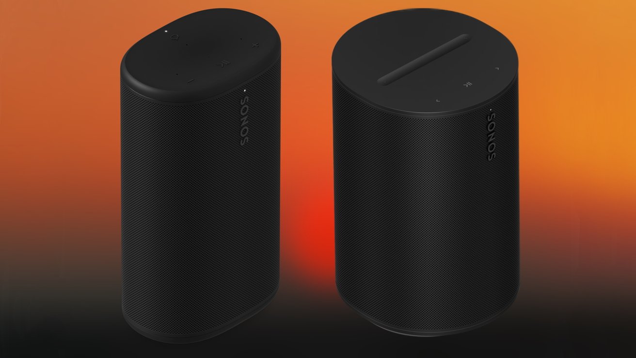 Two tall black Sonos wireless speakers with rounded edges and touch controls, standing side by side against a warm orange to black gradient background