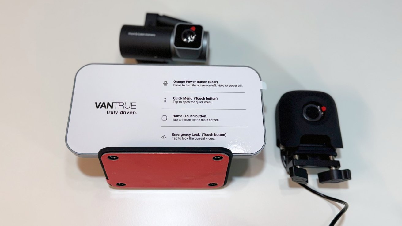 Vantrue dash cam system on a table, showing main screen with labeled touch buttons and two separate camera modules, one with mounting bracket and attached cable