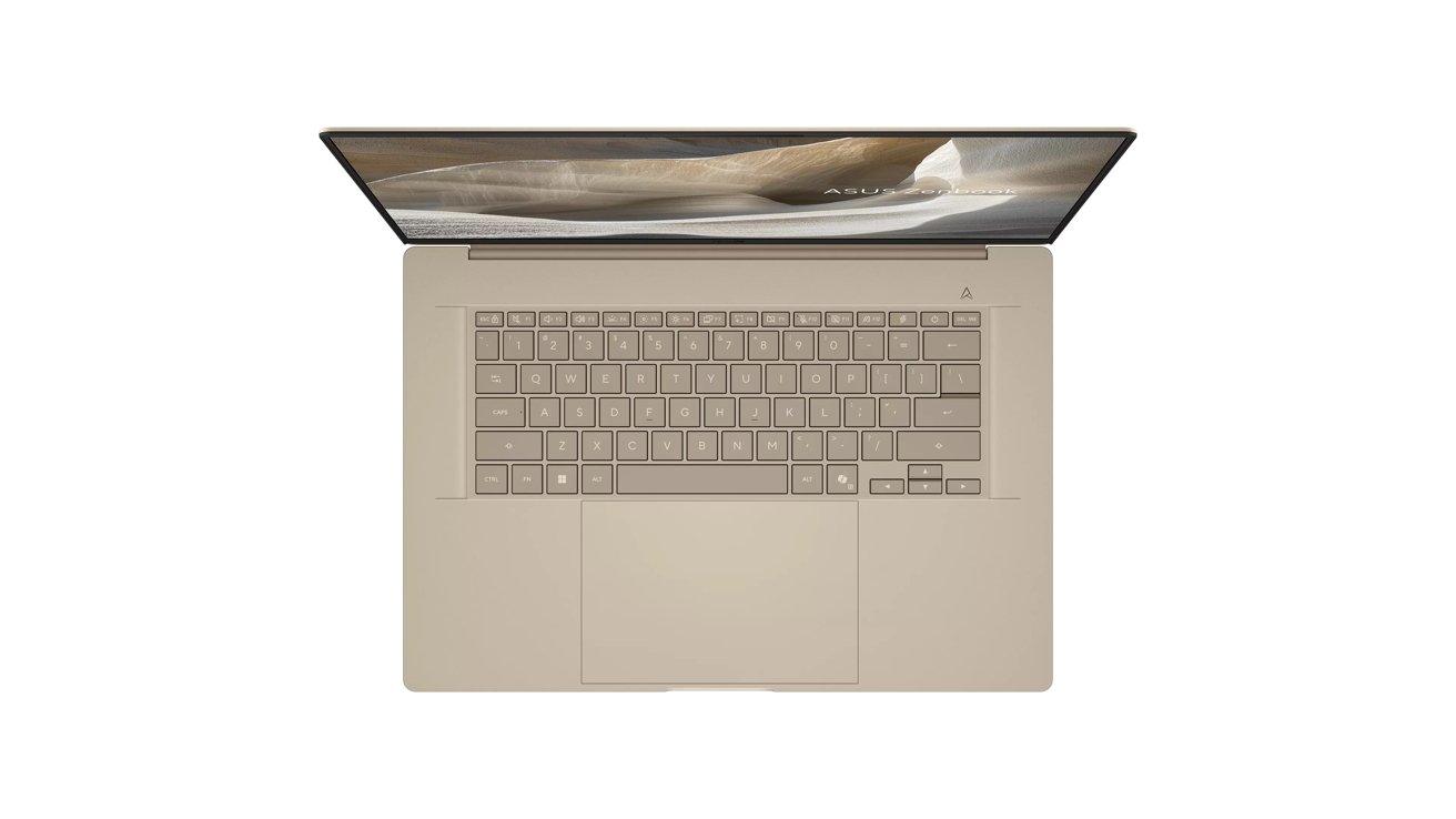 Top view of an open beige laptop with full keyboard, large centered touchpad, and thin-screen display showing a soft desert landscape background
