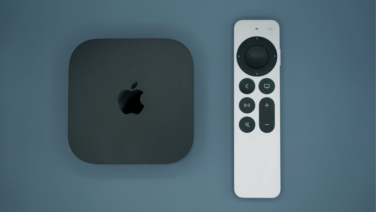 Black Apple TV box next to a slim white remote with circular touchpad and media control buttons, both resting on a flat blue-gray surface.